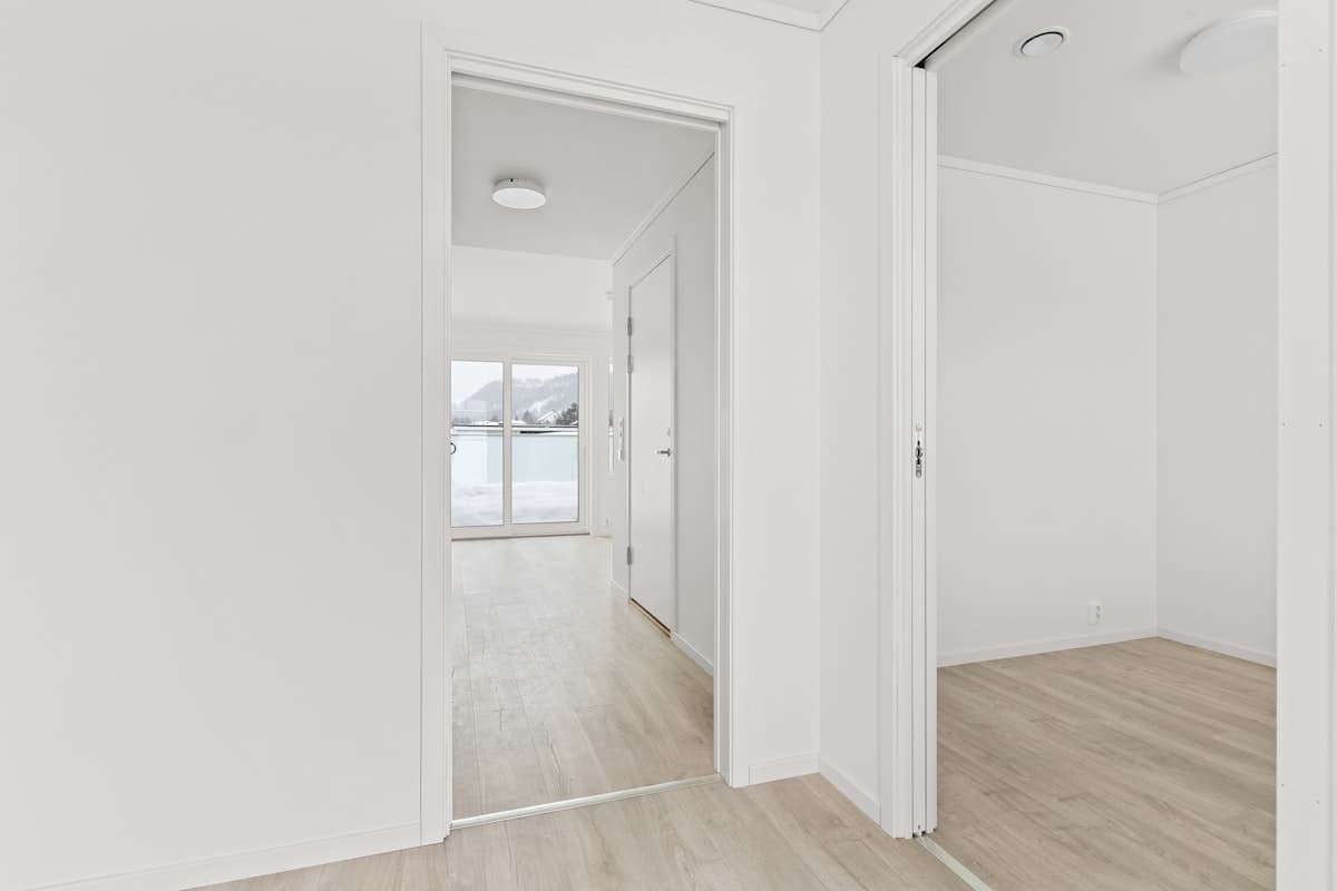 Tomt rum med vita väggar och trägolv redo för inflyttning